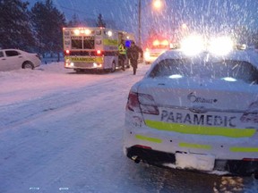 Paramedics attend to a car stranded in the ditch during a snowstorm in Ottawa.