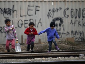 A migrant girl carrying bottle with water in the make shift refugee camp at the northern Greek border point of Idomeni, Greece, Friday, March 18, 2016. More than 46,000 people are trapped in Greece, after Austria and a series of Balkan countries stopped letting through refugees who reach Greece from Turkey and want to go to Europe's prosperous heartland while Greece wants refugees to move from Idomeni to organized shelters.