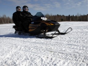 A snowmobile zooms past the spot where full-time Ottawa firefighter, Shawn Mathieson, was killed in a snowmobile crash after a head-on collision Friday March 04, 2016.