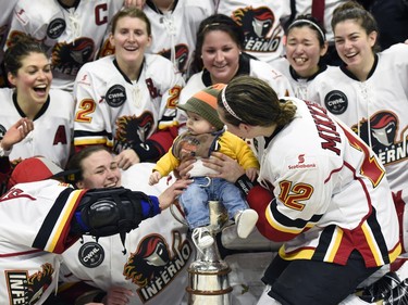 Calder Reid, son of coach Scott Reid and player Meaghan Mikkelson-Reid (12, right) gets placed in the Clarkson Cup trophy after their win over Les Canadiennes de Montreal in Canadian Women's Hockey League final action, Sunday March 13, 2016, in Ottawa.