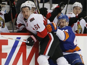 New York Islanders defenseman Calvin de Haan (44) holds Ottawa Senators right wing Mark Stone (61) against the boards during the first period of an NHL hockey game in New York, Wednesday, March 23, 2016.