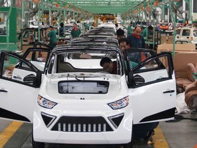 Workers assemble electric cars in a factory in Zouping, east China's Shandong province on September 16, 2014 .China's outbound investment more than doubled in August to 12.62 billion USD, data showed, far outstripping foreign direct investment (FDI) into the country, which fell to a four-year low. CHINA OUT