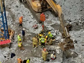 Fire service teams work to rescue a construction worker at the bottom of a 100-foot-pit at Preston Street near Carling on Wednesday.