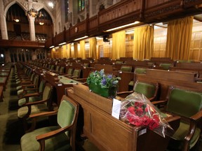 Flowers and a card of sympathy are placed in honour of former Finance Minister Jim Flaherty on a desk in the House of Commons on Parliament Hill in Ottawa on Friday, April 11, 2014. Flaherty died suddenly Thursday of an apparent heart attack. He was 64.
