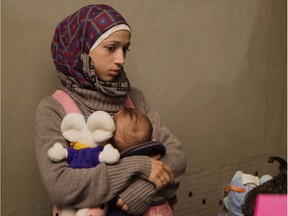 Young refugee woman carrying a baby stands at the platform upon arrival onboard a special train coming from Munich at the railway station in Berlin Schoenefeld on September 13, 2015. Around 700 migrants were sent from Munich as the Bavarian city is at the limit of its capacity to welcome refugees arriving en masse in Germany, police warned Sunday, a day after 13,000 asylum-seekers reached the city.