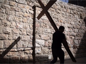 A Catholic pilgrim carries a wooden cross along the Via Dolorosa (Way of Suffering) in Jerusalems Old City during the Good Friday procession on March 25, 2016.  Many Christian pilgrims took part in processions along the route where according to tradition Jesus Christ carried the cross during his last days.