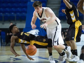 The Dalhousie Tigers' Jordan Aquino-Serjue, left, falls after colliding with the Carleton Ravens' Mitchell Wood during a semifinal at the national university basketball championship in Vancouver on Saturday, March 19, 2016.