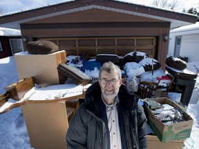 Kit Pullen stands in front of the pile of belongings, including furniture, a Wii gaming console and personal items, left behind by someone in a moving truck overnight on his driveway, at his home in Ottawa, on Wednesday, March 2, 2016. A neighbour reported seeing a U-Haul truck outside the home at 4:30 a.m., and people moving around out front.