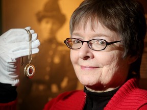 Louise Schwartz holds up a locket that was passed down to her godmother from Georgina Pope (pictured in the background), the first matron of the Canadian Army Medical Corps. The pendant has been bequeathed to the Canadian War Museum.