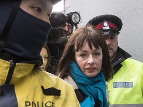 Lucy DeCoutere leaves the Toronto courthouse escorted by police following the reading of the verdict in the Jian Ghomeshi sexual assault trial on Thursday, March 24, 2016.