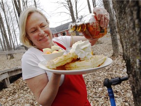 Moira Wilkie, manager at Temple's Sugarbush, soaks a plate of waffles with some of their maple syrup Wednesday next to a tapped maple tree Wednesday.