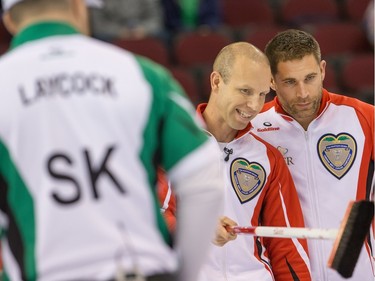 Pat Simmons (L) and John Morris (R) of Team Canada confer on their next shot against Team Saskatchewan as the Tim Horton's Brier continues on Sunday at TD Place in Ottawa.