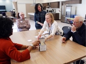 Patient John M., second from left, and John C., right, play cards with student Suzanne Mondoux, third from right, and staff members Shirley Chennette, second from right, and Linda Boakye in the new Algonquin College health-care room.