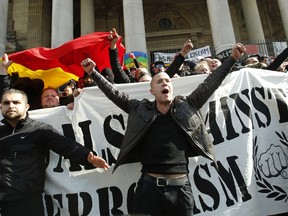 Right wing demonstrators chant slogans next to one of the memorials to the victims of the recent Brussels attacks, at the Place de la Bourse in Brussels, Sunday, March, 27, 2016. In a sign of the tensions in the Belgian capital and the way security services are stretched across the country, Belgium's interior minister appealed to residents not to march Sunday in Brussels in solidarity with the victims."We understand fully the emotions," Interior Minister Jan Jambon told reporters. "We understand that everyone wants to express these feelings."