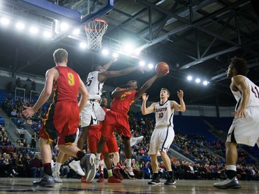 Calgary Dinos' David Kapinga, centre, attempts a shot as Carleton Ravens' Ryan Ejim (45) and Connor Wood (10) defend during CIS men's national university basketball championship final game action in Vancouver, B.C., on Sunday March 20, 2016.
