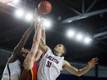 Calgary Dinos' Matt Letkeman, centre, vies for the rebound against Carleton Ravens' Guillaume Payen Boucard, right, and Ryan Ejim during CIS men's national university basketball championship final game action in Vancouver, B.C., on Sunday March 20, 2016.