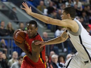 Calgary Dinos' Thomas Cooper, left, drives to the net against Carleton Ravens' Guillaume Payen Boucard during CIS men's national university basketball championship final game action in Vancouver, B.C., on Sunday March 20, 2016.
