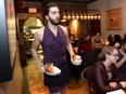 Union 613 staff Tristan Bragaglia-Murdock carries food while wearing a tight skirt and high heels, during an event highlighting sexist dress codes and discrimination against women in the service industry, Wednesday, March 9, 2016 in Ottawa.