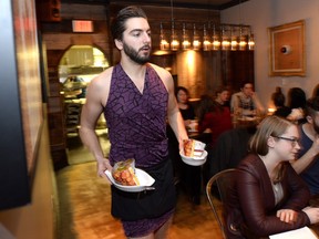 Union 613 staff Tristan Bragaglia-Murdock carries food while wearing a tight skirt and high heels, during an event highlighting sexist dress codes and discrimination against women in the service industry, Wednesday, March 9, 2016 in Ottawa.