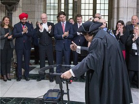 Under the watchful eye of fellow Parliamentarians including Prime Minister Justin Trudeau (C), friends and family, Mauril Bélanger, M.P. for Ottawa Vanier, gives the Prime Minister a thumbs up as he passes through the Rotunda as he takes part in the Speaker's Parade, following the Mace while heading to the House of Commons where he served as honorary Chair Occupant in the House of Commons. (Wayne Cuddington)