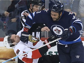 Winnipeg Jets defenceman Dustin Byfuglien (right) drops  Ottawa Senators forward Mark Stone with a body check during NHL action in Winnipeg on Wed., March 30, 2016.