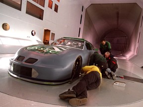 In this file shot, technicians make some adjustments to a racing car before conducting tests at the National Research Council's wind tunnel in Ottawa.