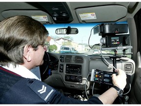 A mobile photo radar operator calibrates a camera unit while waiting for speeders on a Winnipeg street.