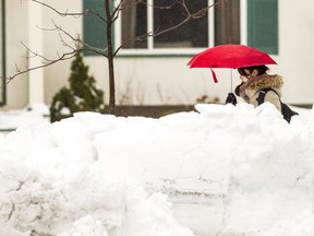 A woman walks along Evered Ave Thursday after a spring snowfall dumped heavy wet snow across the region Wednesday, April 6.