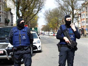 Belgian police officers stand guard in a street in Etterbeek while their colleagues search a warehouse in relation with terrorists arrests in Belgium, on April 09, 2016.  A sixth person was arrested during raids on April 8, 2016 over the Brussels airport and metro bombings which netted top Paris attacks suspect Mohamed Abrini, the Belgian prosecutor's office said. /