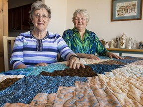 Betty Giffin, left, and Blanche Dunn are, respectively, founder and president of Victoria's Quilts Canada, a not-for-profit charity that provides hand-made quilts for cancer patients. On the table in front of them is the organization's 50,000th quilt, which will be given away this week.