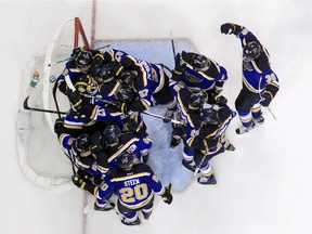 Members of the St. Louis Blues gather around goalie Brian Elliott following the Blues' 3-2 victory over the Chicago Blackhawks in Game 7 of an NHL hockey first-round Stanley Cup playoff series Monday, April 25, 2016, in St. Louis. The Blues won the series 4-3.