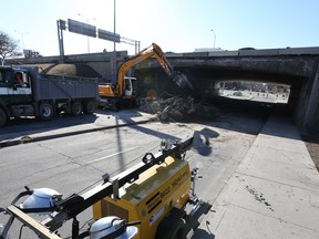 Crews clean up a concrete edge which was removed off the Queensway overpass at Elgin Street in Ottawa Thursday April 14, 2016.  Elgin Street under the 417 overpass continues to be closed Thursday.