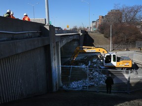 Crews clean up a concrete edge which was removed off the Queensway overpass at Elgin Street in Ottawa Thursday April 14, 2016.