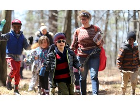 Ottawa Forest and Nature School educator Carrie Komesch, centre right, leads a class out of the woods with a jar for specimens.