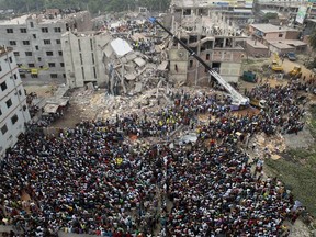 FILE - In this April 25, 2013 file photo, Bangladeshi people gather as rescuers look for survivors and victims at the site of Rana Plaza building that collapsed a day before, in Savar, near Dhaka, Bangladesh. A delegation of the U.S. Trade Representative's office is on a five-day visit to Bangladesh ending Wednesday, Sept. 23, 2015, to see the improvement of safety standards at factory sites and changes to legal documents allowing for wider workers' rights, key conditions for regaining the Generalized System of Preferences facility under which the United States allows imports of more than 5,000 goods from 122 of the world's poorest countries with low or zero-tariff benefits. The trade benefit was withdrawn after the collapse of Rana Plaza, a building complex housing five garment factories outside the capital, Dhaka in 2013. The garment industry is crucial to Bangladesh's economy as it employs about 4 million workers, mostly rural women, and many other sectors including banks are heavily dependent on it.