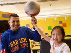 Harlem Globetrotter "El Gato" Melendez spins a basketball on the finger of CHEO patient Sophia Hung,7,  during a visit to the hospital as part of the Globetrotters' Smile Patrol. The Globetrotters will be visiting the Canadian Tire Centre on April 10. Monday April 4, 2016. Errol McGihon
