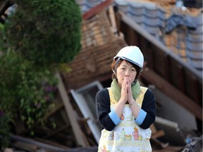 In this Saturday, April 16, 2016, file photo, a resident stands in front of damaged house in Mashiki, Kumamoto prefecture, Japan. A powerful earthquake struck southwestern Japan early Saturday, barely 24 hours after a smaller quake hit the same region.