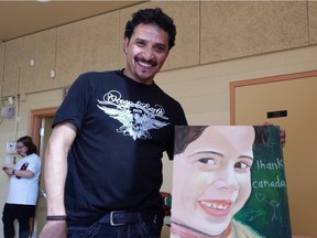 Mohamed Ali shows his painting representing a Syrian child crying tears of joy at a dinner for Syrian refugees like him served by Young Voices Can, made up of Jewish and Muslim high school students, at the Carleton Heights Community Centre Sunday.