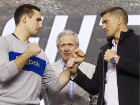 Rory MacDonald, left, and Stephen Thompson square up for the cameras, while Tom Wright, UFC executive vice-president and general manager for Canada, Australia and New Zealand, center, looks on.
