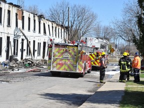 Smiths Falls firefighters confer early Saturday afternoon amid the damage left by a fire at a row house complex on Robinson Avenue.