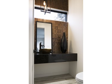 1st place, powder room: Candace Sutcliffe and Alex Diaz of Art House Developments balanced weighty masculine materials such as copper tile and bronze sink and hardware with a floating granite counter and lighter floor tile for a welcoming look.