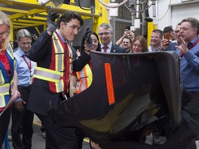 Prime Minister Justin Trudeau celebrates after he finishes the work on a Chrysler hood as he tours the Magna Polycon Industries plant in Guelph, Ont. on Thursday, April 14, 2016. THE CANADIAN PRESS/Hannah Yoon ORG XMIT: HLY104