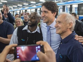 Prime Minister Justin Trudeau stops for a photograph with workers as he tours a garage of the Montreal Transportation Commission, Wednesday, April 6, 2016 in Montreal. THE CANADIAN PRESS/Paul Chiasson ORG XMIT: pch106