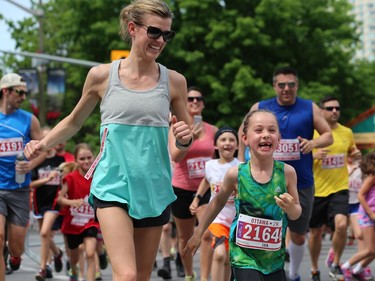 Lea Charbonneau, right, is all smiles as she runs in the Kids 2K run.