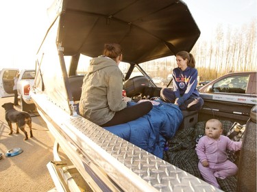 A family takes refuge in the back of their boat after evacuation at a rest stop near Fort McMurray, Alta., on Wednesday, May 4, 2016. A wildfire has put all of Fort McMurray under a mandatory evacuation order which means that about 70,000 people who live in Fort McMurray are being told to flee the city.