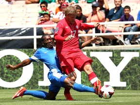 Nicolas Zaire #2 of Martinique kicks the ball away from Marcel De Jong #17 of Canada during the first round of the 2013 CONCACAF Gold Cup at the Rose Bowl on July 7, 2013 in Pasadena, California.