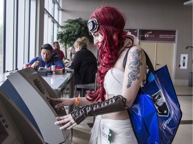 Dressed as Capable from the film Mad Max: Fury Road, Jade Bacon uses an ATM at Comiccon. (Bruce Deachman, Ottawa Citizen)
