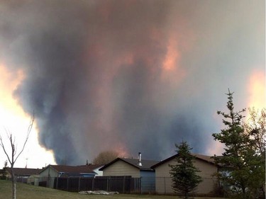Fire burns and smoke fills the air near homes in Fort McMurray, Alberta on Tuesday May 3, 2016. Raging forest fires whipped up by shifting winds sliced through the middle of the remote oilsands hub city of Fort McMurray Tuesday, sending tens of thousands fleeing in both directions and prompting the evacuation of the entire city.