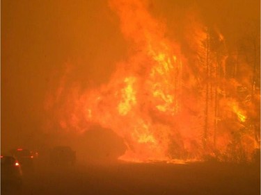 Fire burns near a road in Fort McMurray, Alberta on Tuesday May 3, 2016. Raging forest fires whipped up by shifting winds sliced through the middle of the remote oilsands hub city of Fort McMurray Tuesday, sending tens of thousands fleeing in both directions and prompting the evacuation of the entire city.