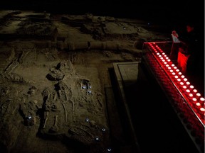 In this Feb. 11, 2014 photo, a visitor takes photos at a burial site at Nanjing Massacre Memorial Hall in Nanjing, in eastern China's Jiangsu province. The Tokyo shrine and the memorial hall in Nanjing, as Nanking is now called, are physical embodiments of divergent views of history that still strain China-Japan relations, 70 years after the war.